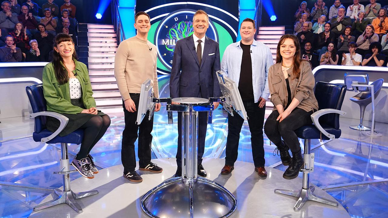 © ORF/Stefan Gregorowius Im hell beleuchteten "Millionenshow"-Studio stehen und sitzen Anna Edlinger, Kilian Guggenberger, Anna Edlinger (Wien), Kilian Guggenberger und Tanja Spanner mit Armin Assinger in der Mitte um den Quiz-Pult, während ein applaudierendes Publikum im Hintergrund zu sehen ist.