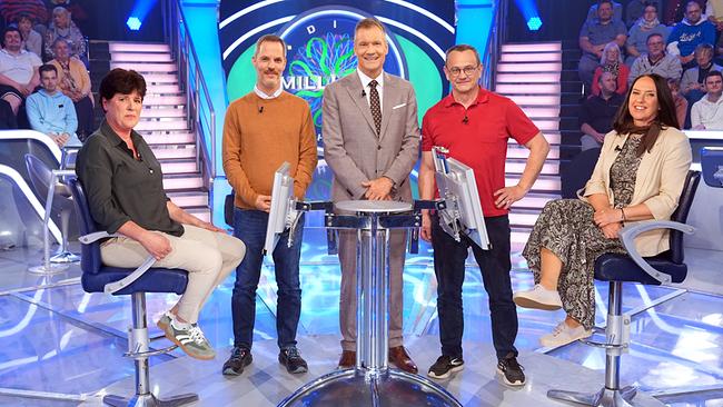 Sonja Fischer, Pierre Douay, Armin Assinger, Gerhard Brunner und Marion Dygryn stehen gemeinsam um den "Millionenshow"-Pult im TV-Studio mit Publikum im Hintergrund.