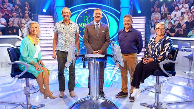 © ORF/Stefan Gregorowius Marion Wickström, Peter Kafol, Armin Assinger, Luigi Thurner und Elfi Joham stehen lächelnd um den "Millionenshow"-Pult im TV-Studio mit Publikum im Hintergrund.
