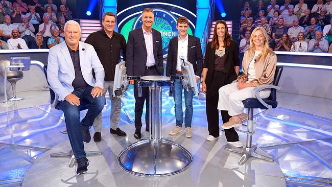 Toni Polster, Andreas Herzog, Armin Assinger, Johannes Aigner, Janine Flock und Lisa Hauser posieren im "Millionenshow"-Studio vor einem applaudiernden Publikum.