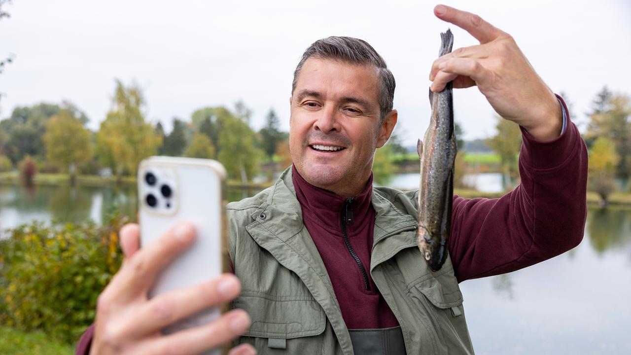 Stolz posiert 'Times-Square'-Wirt Jo für ein Selfie, das seinen erfolgreichen Fischfang dokumentieren soll.