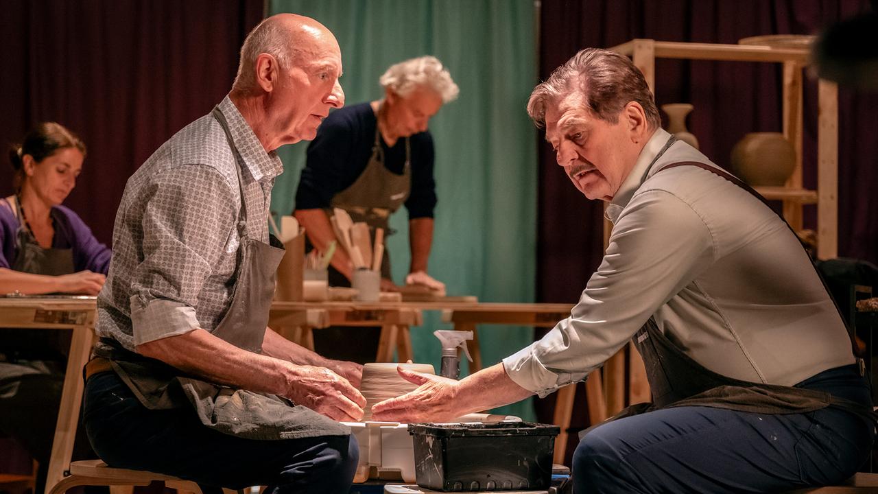 Rene Kleist und Alfons Seywald sitzen sich in einer Töpferwerkstatt an der Töpferscheibe gegenüber.