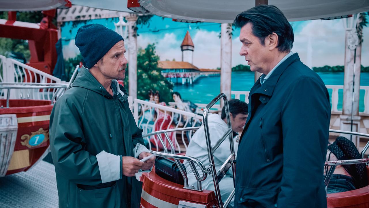 © ORF/Graf Film/Lukas Gnaiger Micha Oberländer und Thomas Komlatschek sprechen vor einem Karussell miteinander.