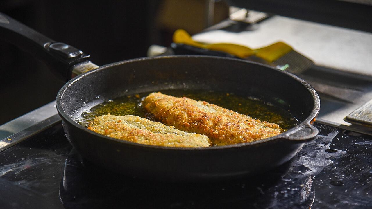 © ORF/Produktion West/Gerhard Mader Zwei goldbraun-knusprige Fischfilets braten in einer Pfanne.