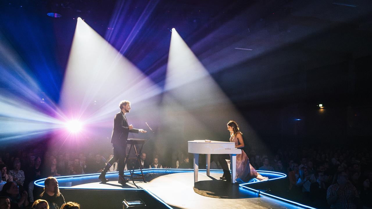 Amélie van Tass am weißen Flügel und Thommy Ten neben einem Keyboard auf der Bühne umgeben vom Publikum.
