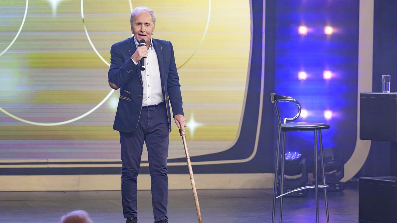 Klaus Eberhartinger mit Mikro und einem Gehstock auf der Bühne bei seiner Performance