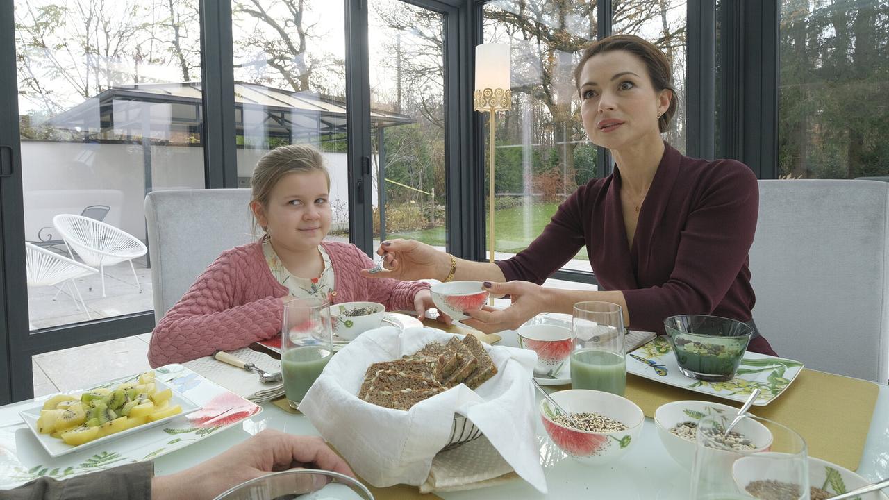 "Faltenfrei": Leonie (Paula Fütterer, li.) und ihre Mutter Fiona (Henriette Richter-Röhl) sitzen am perfekt gedeckten Frühstückstisch und warten auf Stella.
