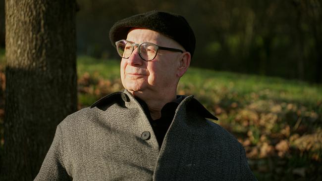 Psychiater, Psychologe und Philosoph Michael Lehofer mit Mütze und Mantel sitzt im Freien an einem Baum umgeben von herbstlicher Natur.