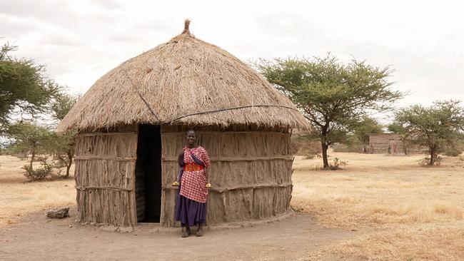 Massai Ndamu Tomas steht neben dem Eingang einer Strohhütte.