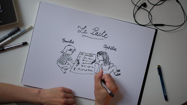 Die Cartoonistin Émilie Tronche beim Zeichnen auf Papier der Illustration mit dem Titel „Le Pacte“, die zwei Freundinnen zeigt.