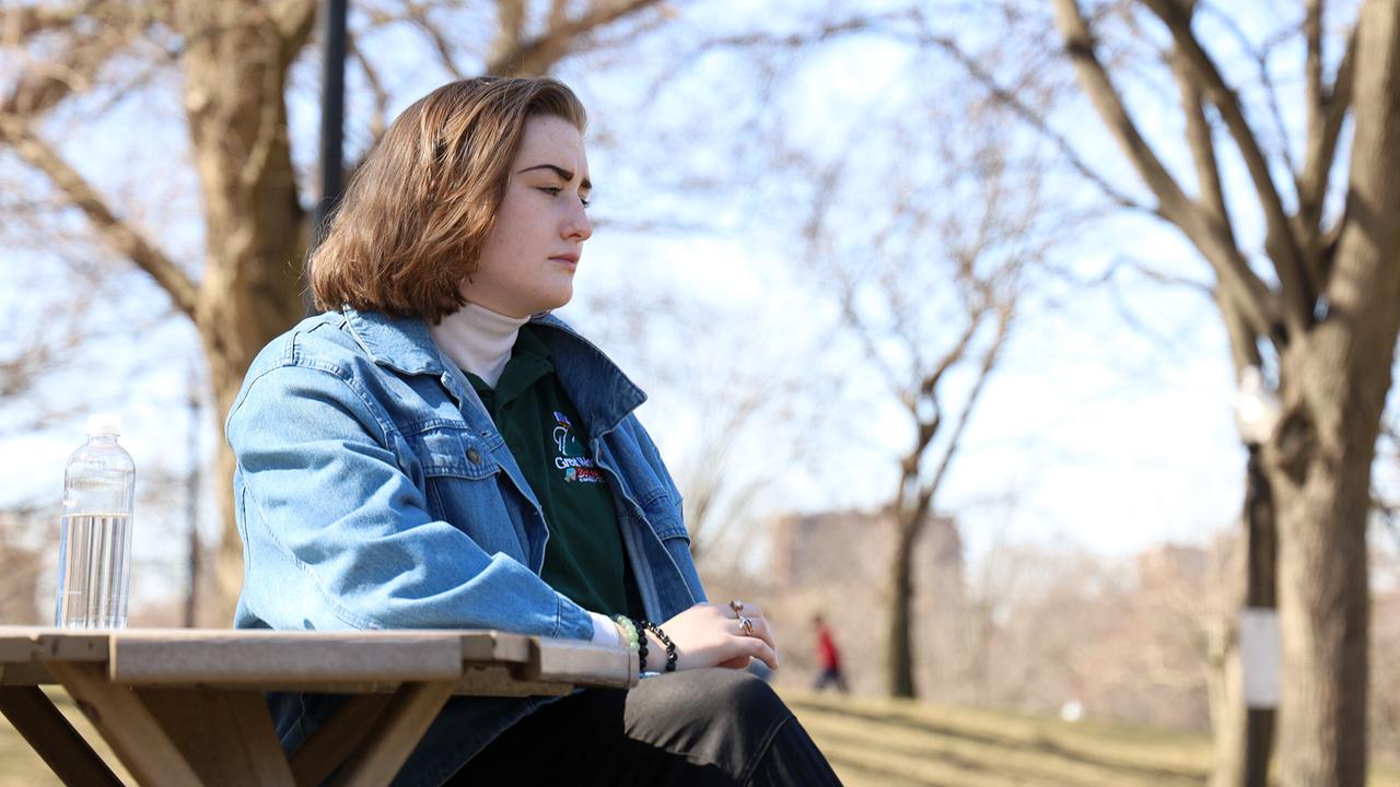 © ORF/PBS/Arte France/Fehling Family Megan sitzt nachdenklich an einem Picknicktisch in einem Park.