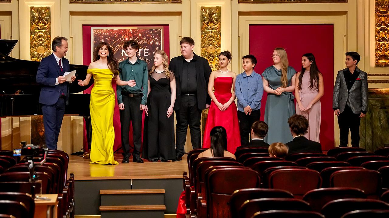 Arno Steinwider und Leona König stehen mit den "Goldene Note"-Semifinalistinnen und -finalisten Adam Benold, Linda Gittmaier, Nico Haidenhofer, Idil Naz Alici, Lukas Maierhofer, Julie Herber und Maria Bendel auf der Bühne in in einem prunkvollen Saal. 