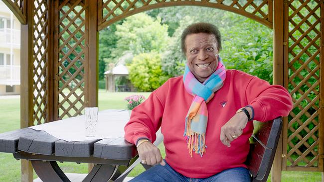 © ORF/FFP Filmproduktion Roberto Blanco sitzt mit buntem Schal und rotem Pullover in einem hölzernen Gartenpavillon.