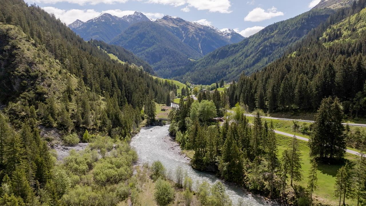 © ORF/Kiwi TV Eine Luftaufnahme zeigt ein langes Tal mit dem Lech, Straße, Wald und schneebedeckten Bergen.
