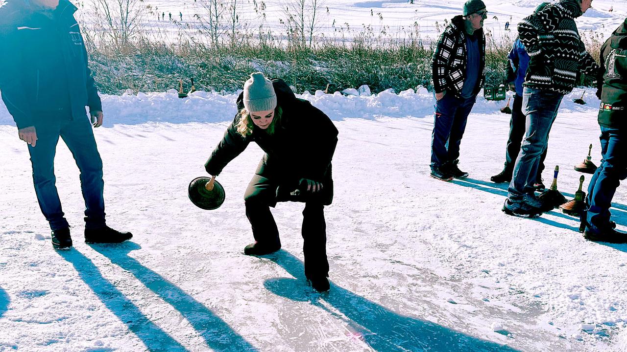 Christine Reiler beim Eisstockschießen am Weissensee umgeben von weiteren Menschen