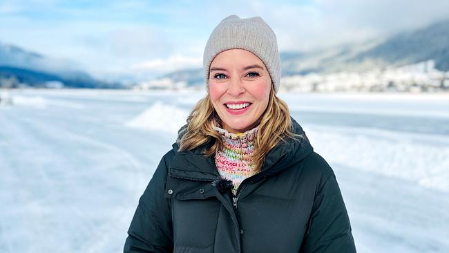 Christine Reiler steht warm eingepackt am Weissensee vor einer weiten, verschneiten Winterlandschaft.