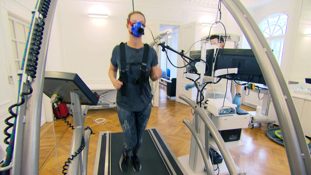 Dr. Christine Reiler demonstriert am Laufband in einem sportwissenschaftlichen Testraum mit Messgeräten, wie sich das Luftvolumen vervielfachen lässt.