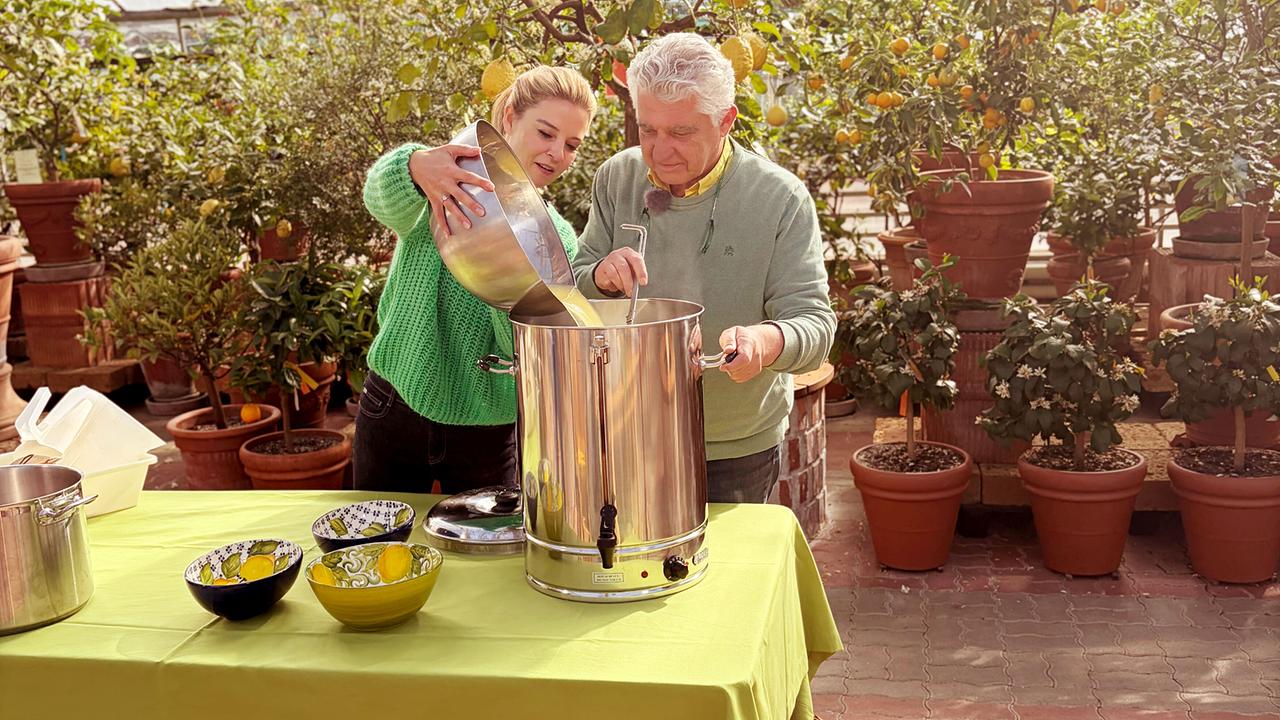 Christine Reiler und Michael Ceron gießen gemeinsam einen Zitronensaft in einen großen Edelstahlkessel.