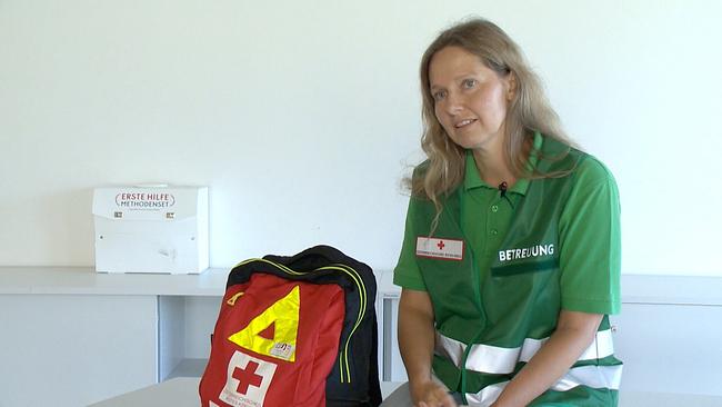 Notfallpsychologin Karin Unterluggauer sitzt auf einer  Medizinliege neben einem Erste-Hilfe-Rucksack