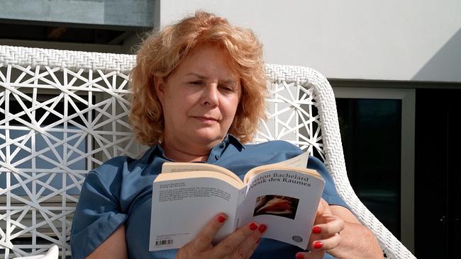 Sandra Häuplik-Meusburger sitzt mit einem Buch auf einer Rattan-Coach.