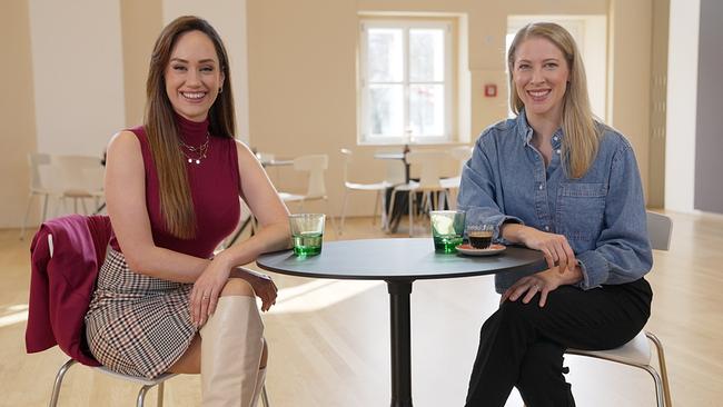 Sasa Schwarzjirg und Maria Angelini-Santner sitzen in einem hellen Raum in der Tanzschule in Linz an einem kleinen runden Café-Tisch und lächeln in die Kamera.