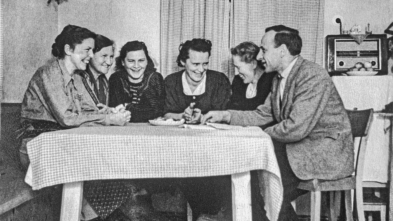 © ORF/SOS Kinderdorf Schwarz-Weiß-Foto: Mitgründerinnen von SOS Kinderdorf sitzen lachend mit Hermann Gmeiner an einem Tisch.