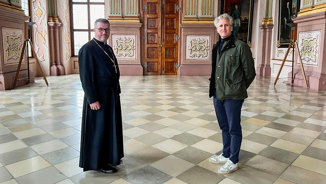 © ORF/Interspot Film/Carlo Hofmann Johann-Philipp Spiegelfeld und Propst MMag. Petrus Stockinger Can. Reg stehen in einem prunkvoll dekorierten Saal mit verzierten Wänden, großer Tür, Gemälden und kariertem Marmorboden des Augustiner-Chorherrenstifts Herzogenburg
