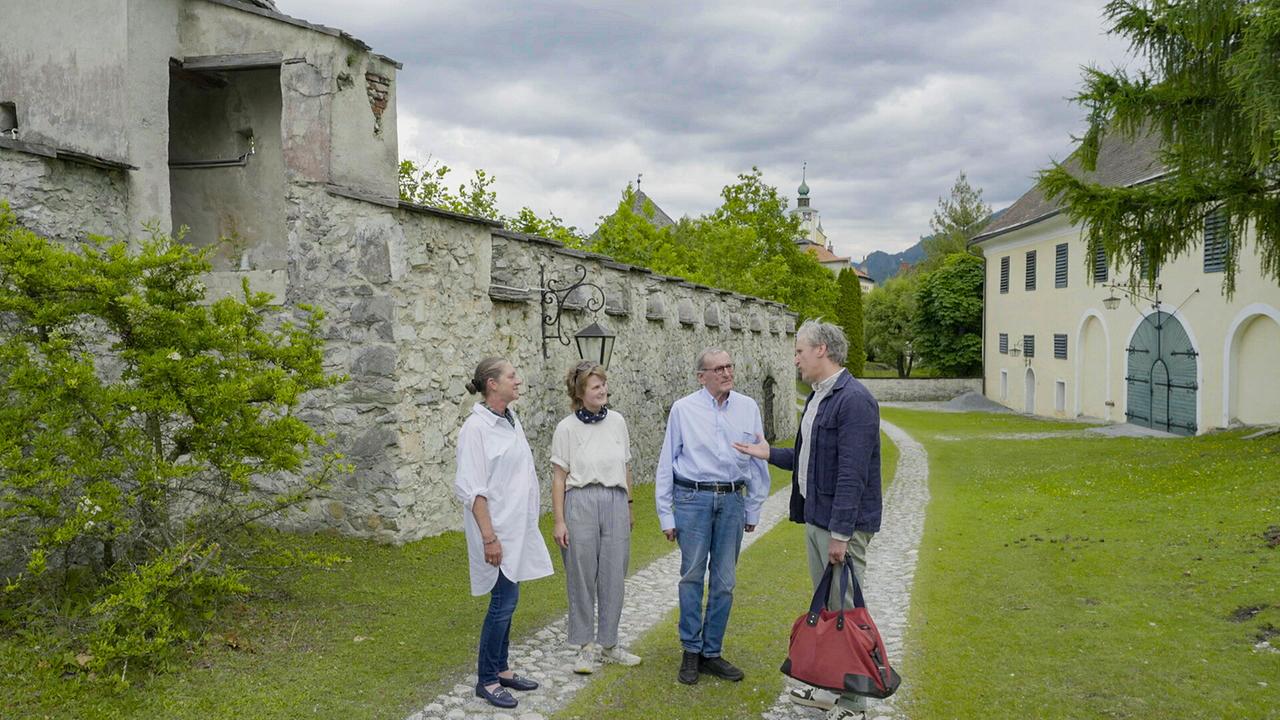 Johann-Philipp Spiegelfeld, Wolfgang Boesch, Marianne Boesch-Leibrecht und Bernadette Boesch stehen vor einer alten Steinmauer von der Burg Strechau und einem gelben Gebäude und unterhalten sich im Freien.
