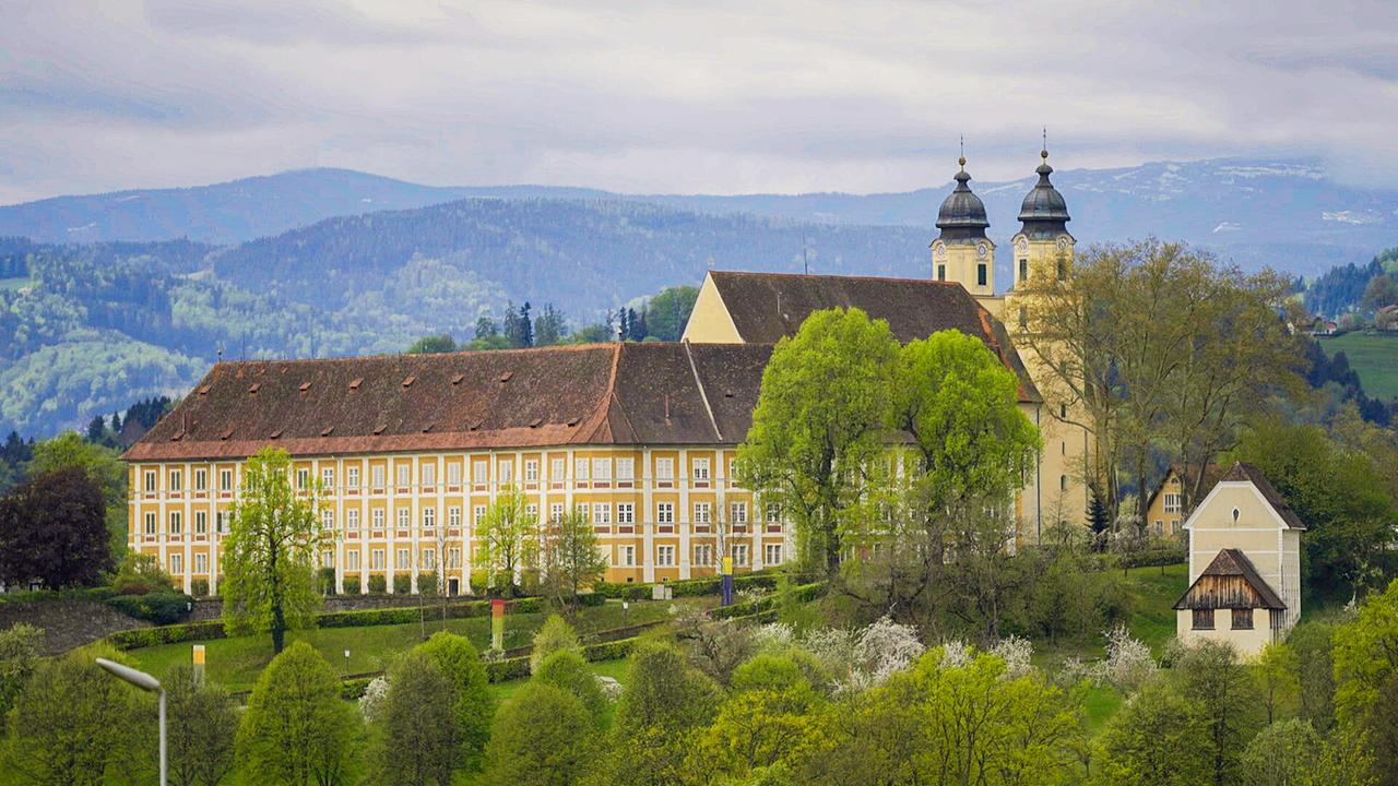 © ORF/Interspot Schloss Stainz mit Doppelturm liegt malerisch eingebettet in einer hügeligen Landschaft.