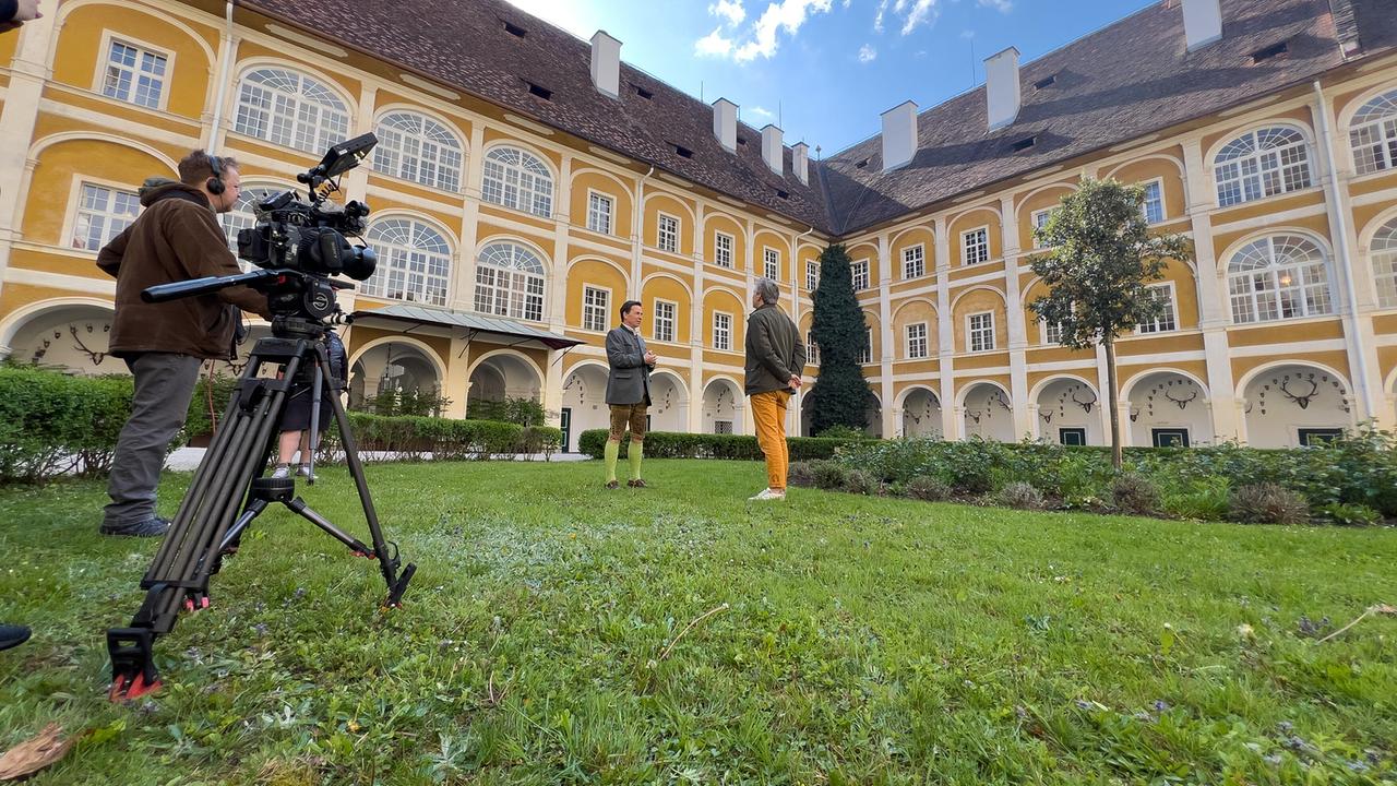 © ORF/Interspot/Philip Pürcher, Carlo Hofmann Johann-Philipp Spiegelfeld steht mit Schlossbesitzer Franz Meran auf einer Wiese im Innenhof von Schloss Stainz