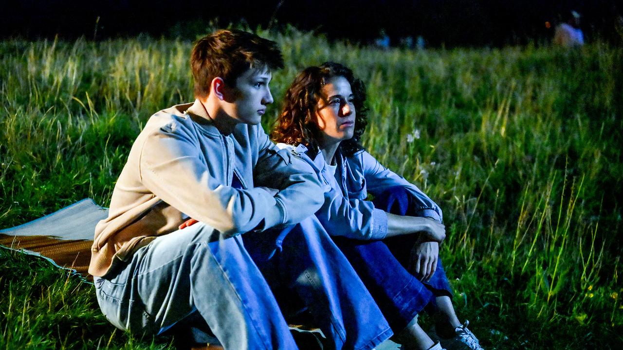 © ORF/BR/maze pictures GmbH/Barbara Bauriedl Florian Kirchberger und Lisa Kirchberger sitzen nebeneinander nachts auf einer Wiese und blicken nachdenklich in die Ferne.