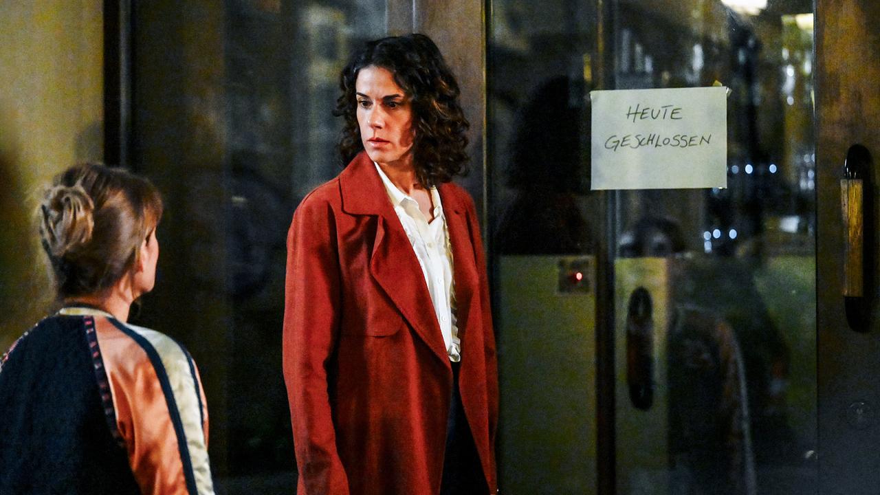 © ORF/BR/maze pictures GmbH/Barbara Bauriedl Lisa Kirchberger in rotem Mantel steht nachts vor einer Glastür mit dem Schild „Heute geschlossen“ und blickt ernst zu Heike Eder.