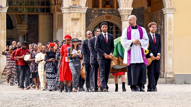 © ORF/BR/maze pictures GmbH/Barbara Bauriedl Eine große afrikanische Trauergemeinde zieht hinter dem Pfarrer Hans Reiser und dem getragenen Sarg durch einen Klosterhof.