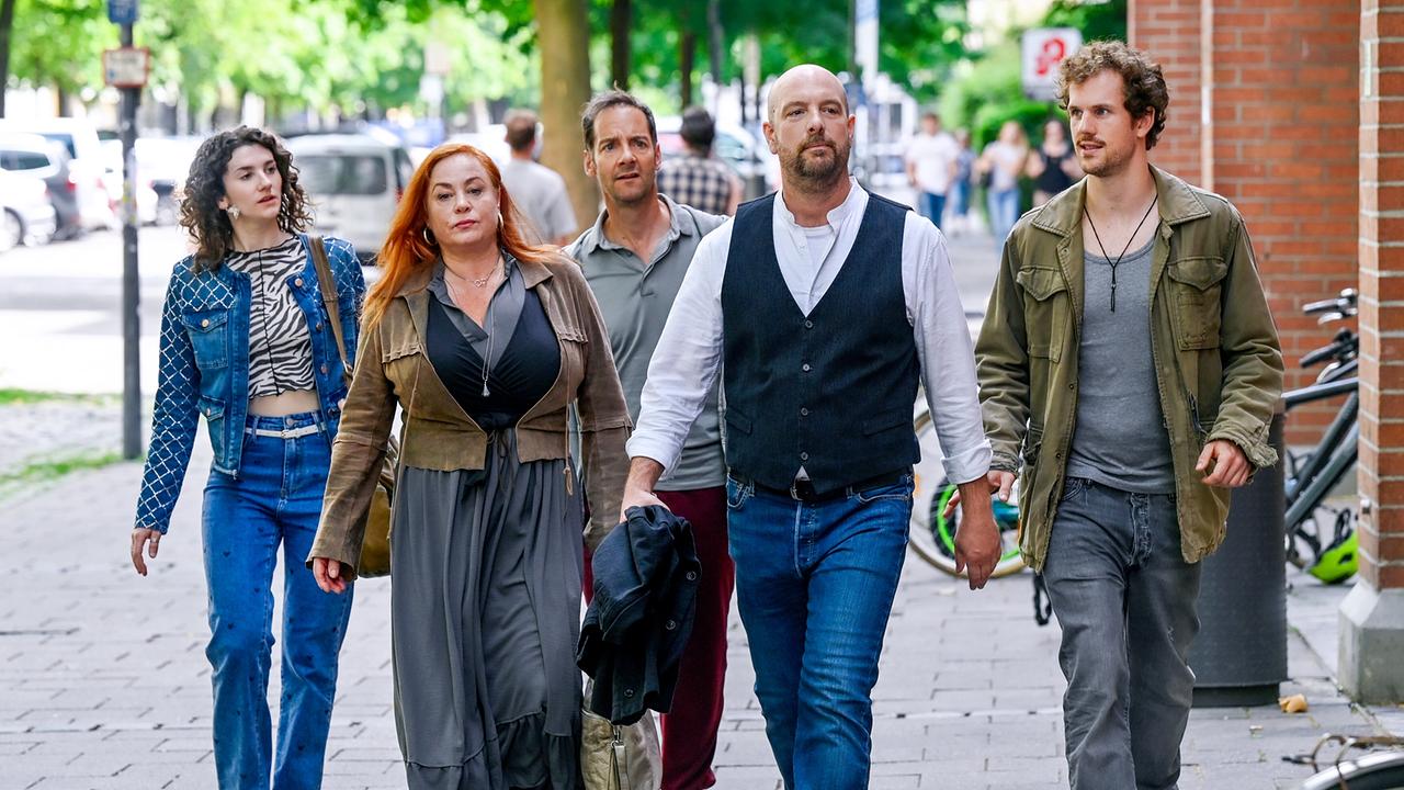 Eine Gruppe von fünf Menschen, an der Spitze Hans Reiser, geht entschlossen gemeinsam auf einem Gehsteig durch die Stadt.