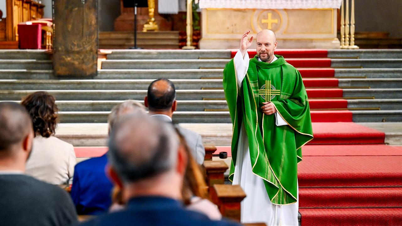 Hans Reiser in grünem Messgewand segnet vor dem Altar die sitzende Gemeinde in einer Kirche.