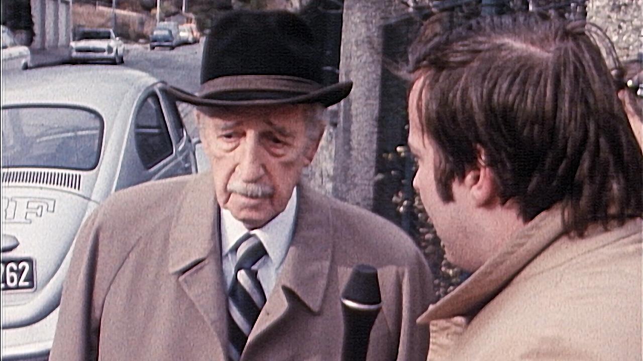© ORF Walter Palmers wird nach seiner Freilassung November 1977 von einem Reporter auf einer Straße mit geparkten Autos interviewt.