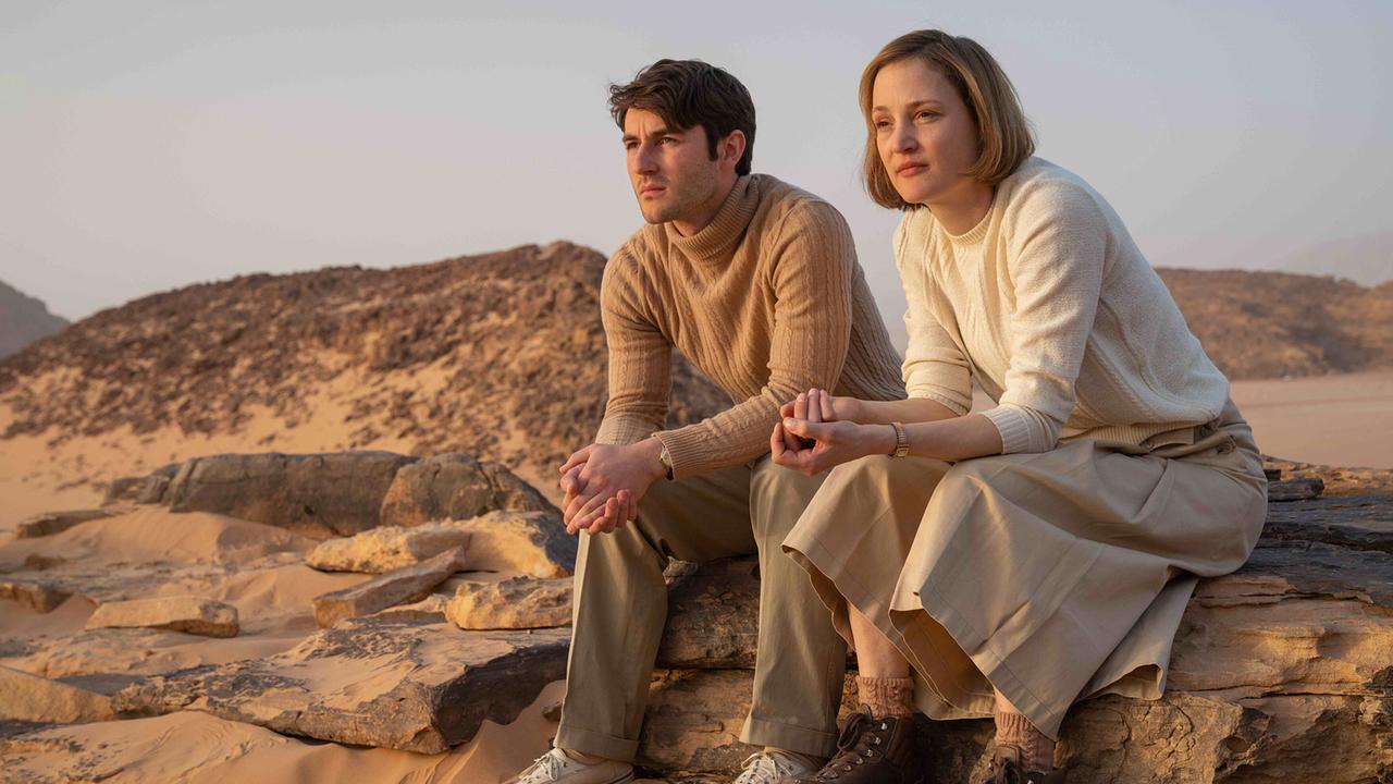 Tobias Resch (Adolf Opel) und Vicky Krieps (Ingeborg Bachmann) sitzen nebeneinander auf Felsen in der Wüste und blicken in die Landschaft.