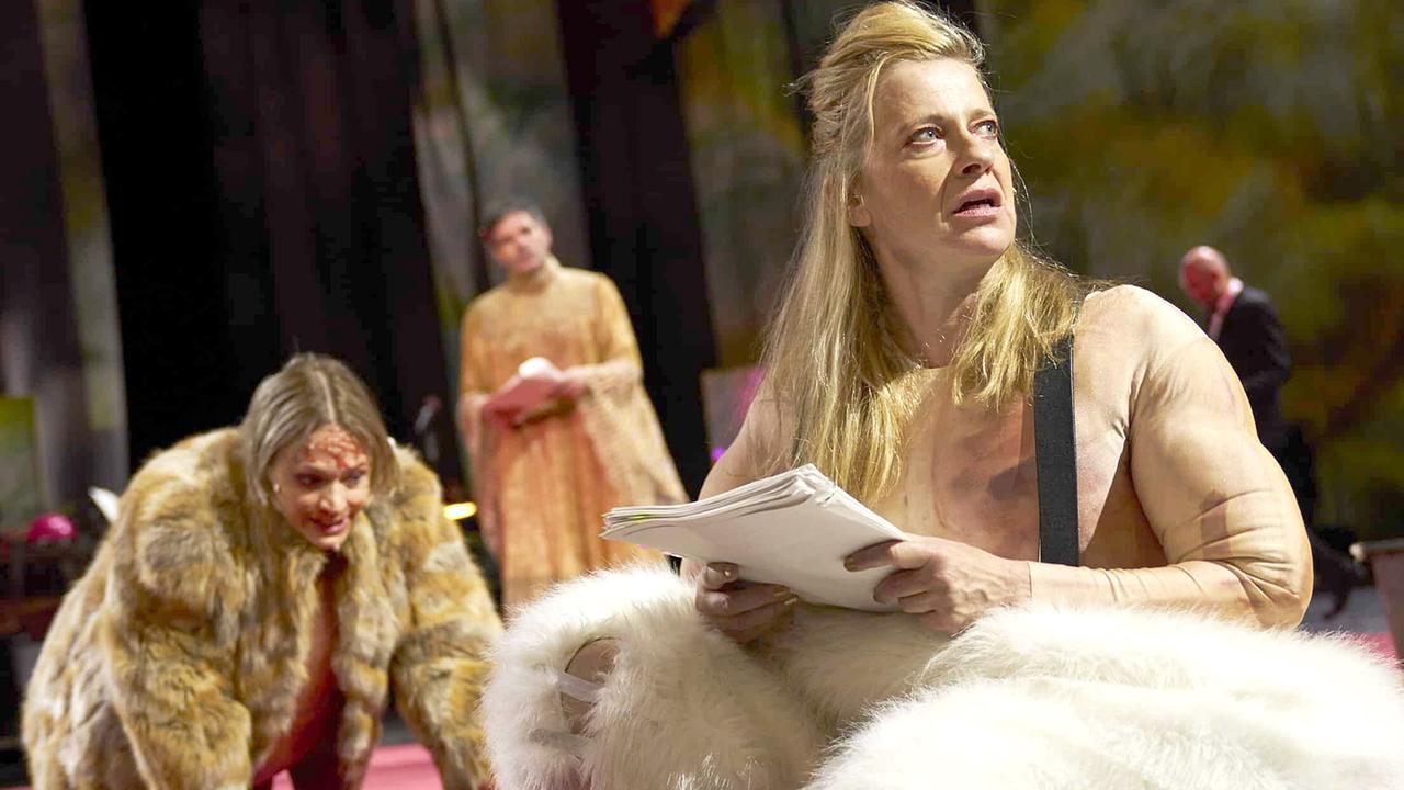 © ORF/SF/BURG/Tommy Hetzel Mavie Hörbiger im Fellmantel und Caroline Peters in einer Fellhose und Thiemo Strutzenberger im Hintergrund auf der Bühne in Elfriede Jelineks Stück „Unter Tieren“ bei den Salzburger Festspielen