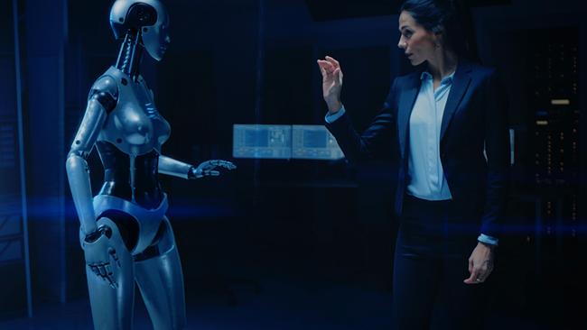 Eine Frau in Businesskleidung interagiert in einem futuristisch beleuchteten Raum mit einem schlanken, silbernen humanoiden Roboter.