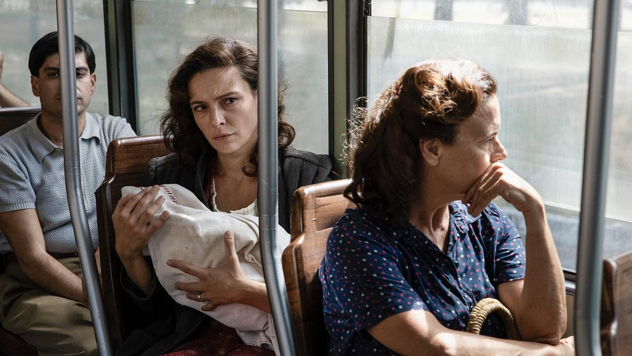 Ida fährt mit dem Neugeborgenen in der Straßenbahn und blickt dabei ernst und nachdenklich.