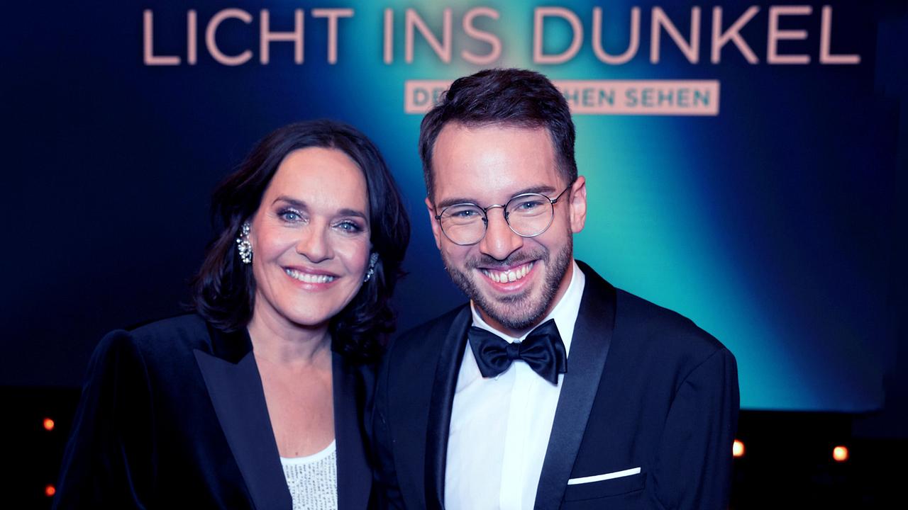 © ORF/Roman Zach-Kiesling Eva Pölzl und Andreas Onea posieren vor einer Media-Wand mit dem Schriftzug „Licht ins Dunkel“.
