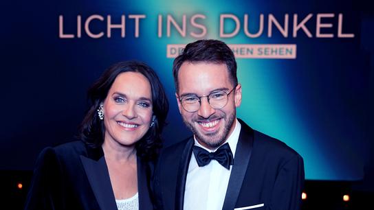 Eva Pölzl und Andreas Onea  posieren vor einer Media-Wand mit dem Schriftzug „Licht ins Dunkel“.