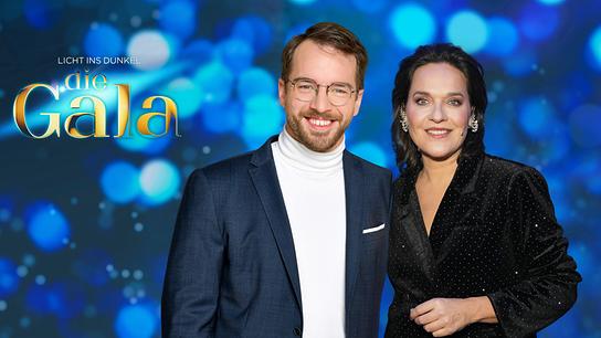 Andreas Onea und Eva Pölzl vor einem blauen Hintergrund mit dem Schriftzug „Licht ins Dunkel - die Gala“. 