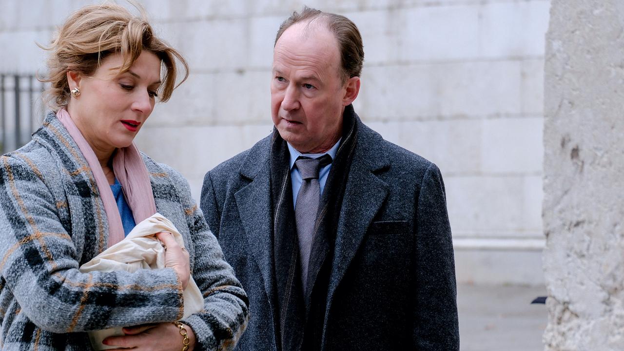 Vor einer Steinmauer stehen Karin Biederstädt, die zu Boden blickt, und Anton Laux nah beieinander.