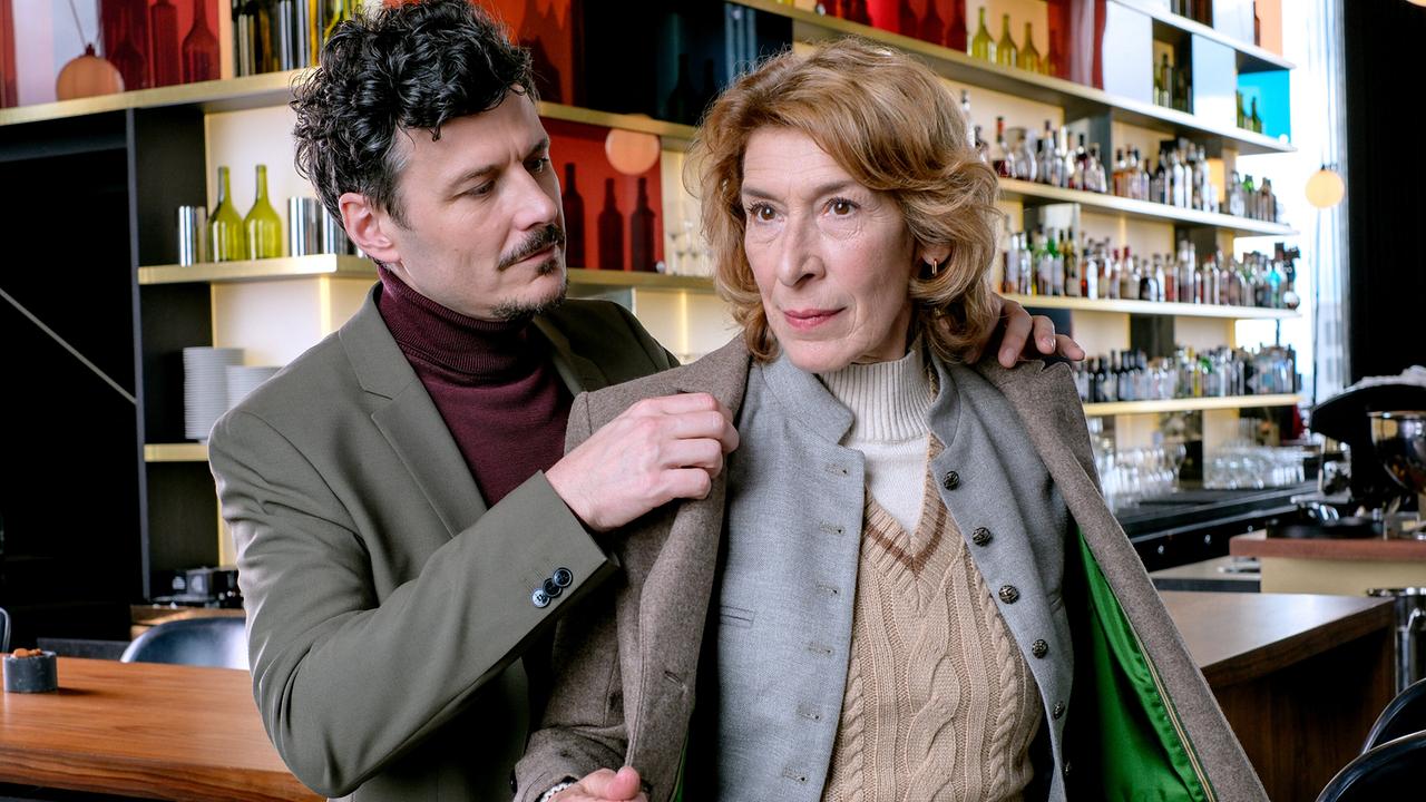 Ricardo Westerhoff hilft Constanze Laux aus ihrer Jacke untertags in einem Lokal an einer Bartheke.