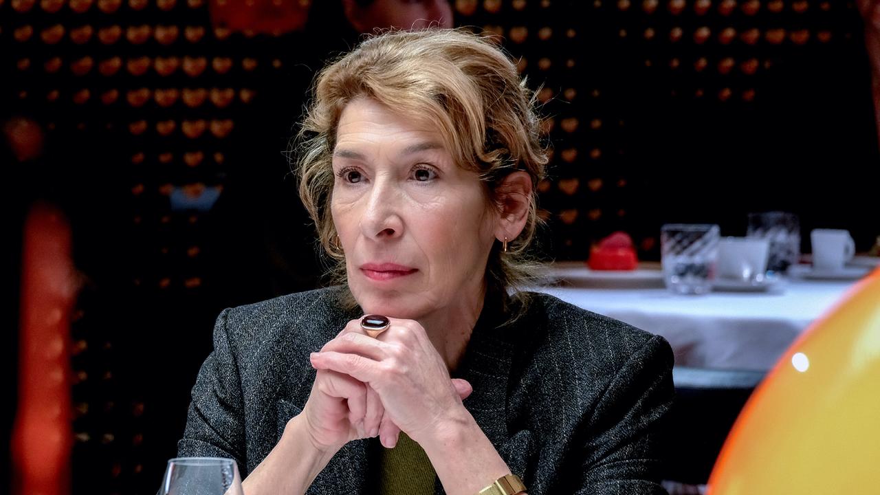 Constanze Laux sitzt ernst blickend an einem Tisch in einem modernen Lokal.