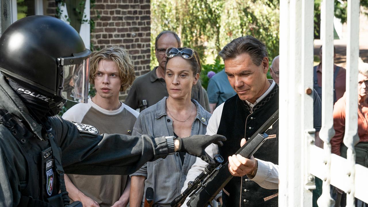 Reimund, Franziska Krings und Guido Berger stehen am Eingangstor zur Reichsbürgergemeinschaft dem SEK gegenüber. 