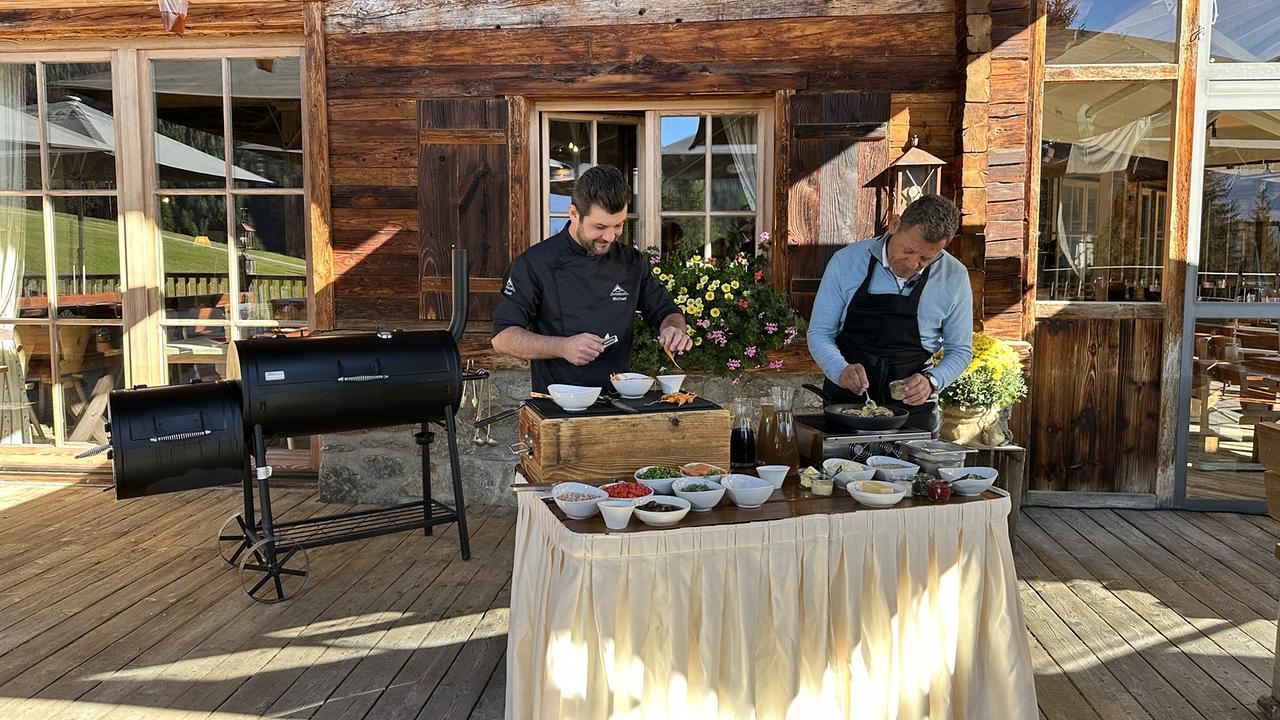 © ORF/Landesstudio Tirol Bei „Mei liabste Speis“ kocht Franz Posch mit einem Koch die traditionelle und robuste „Fisser Gerste“ vor einer Almhütte Speisen an einem großen Smoker-Grill.