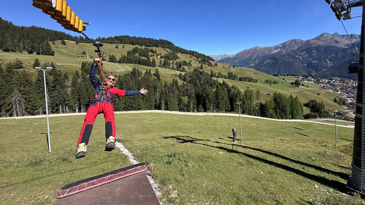 © ORF/Landesstudio Tirol Rasante Abfahrt: Franz Posch probiert den „Serfauser Sauser“ aus und schwebt an einer Zipline über eine Bergwiese mit eindrucksvollem Alpenpanorama.