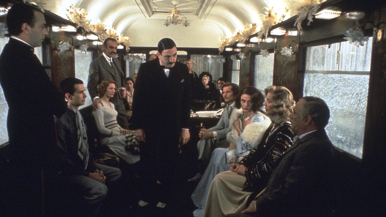 © ORF/Studiocanal Meisterdetektiv Hercule Poirot in der Mitte eines historischen Eisenbahnwaggons, um ihn herum sitzen und stehen Personen, die ihm erwartungsvoll zu ihm blicken
